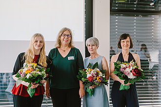 Preisträgerinnen und Vizepräsidentin für Lehre stehen nebeneinander. Die drei Preisträgerinnen halten jeweils einen großen Blumenstrauß