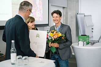 Der Vizepräsident für Lehre überreicht Blumen und Urkunde vom Preis für gute Lehre an Prof. Dr. Michael Jaensch