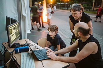 ein Mann zeigt etwas am Laptop bei Abendstimmung