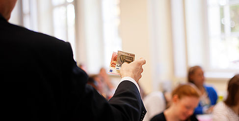 Professor holds banknotes in his hand during a lecture